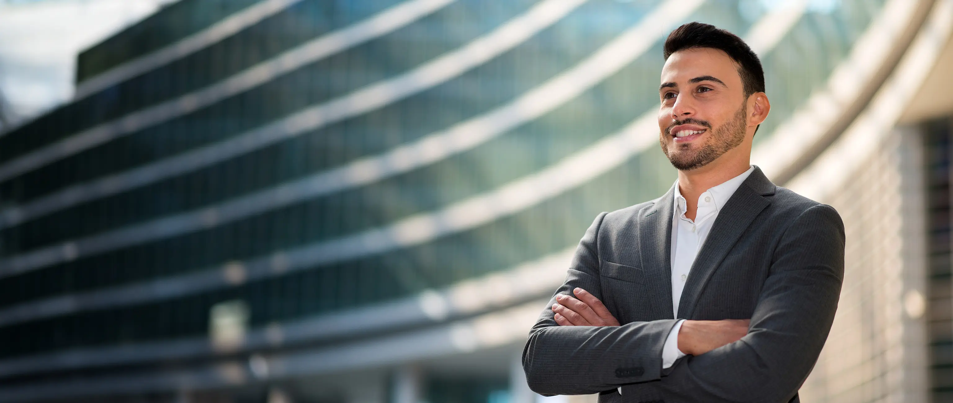 A smiling professional man standing confidently outside a modern corporate building, representing National Bonds EIBOR-linked investment products.