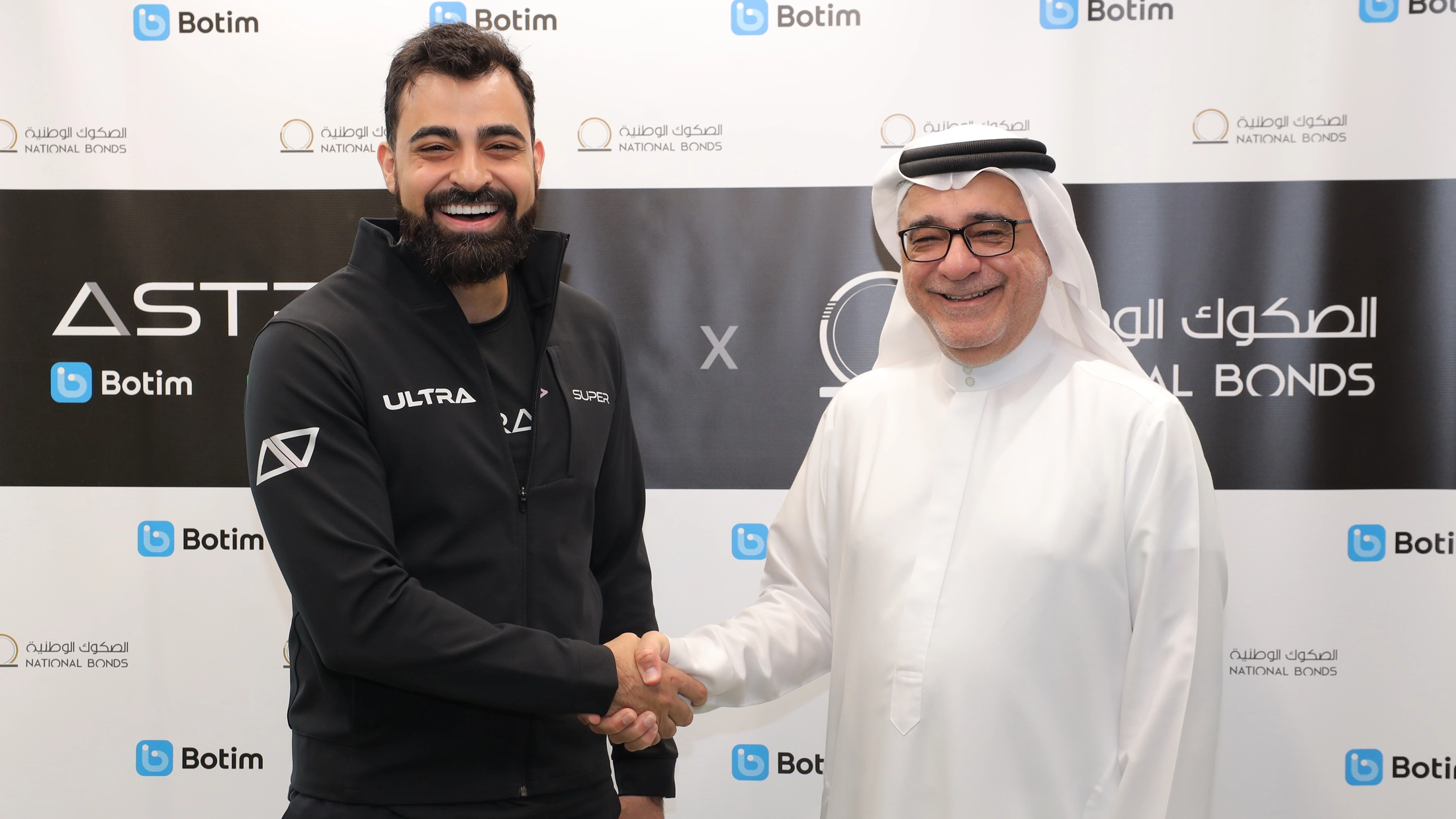 Abdallah Abu Sheikh, CEO of Botim, and Mohammed Qasim Al Ali, Group CEO of National Bonds, shaking hands to announce a strategic partnership for digital savings.