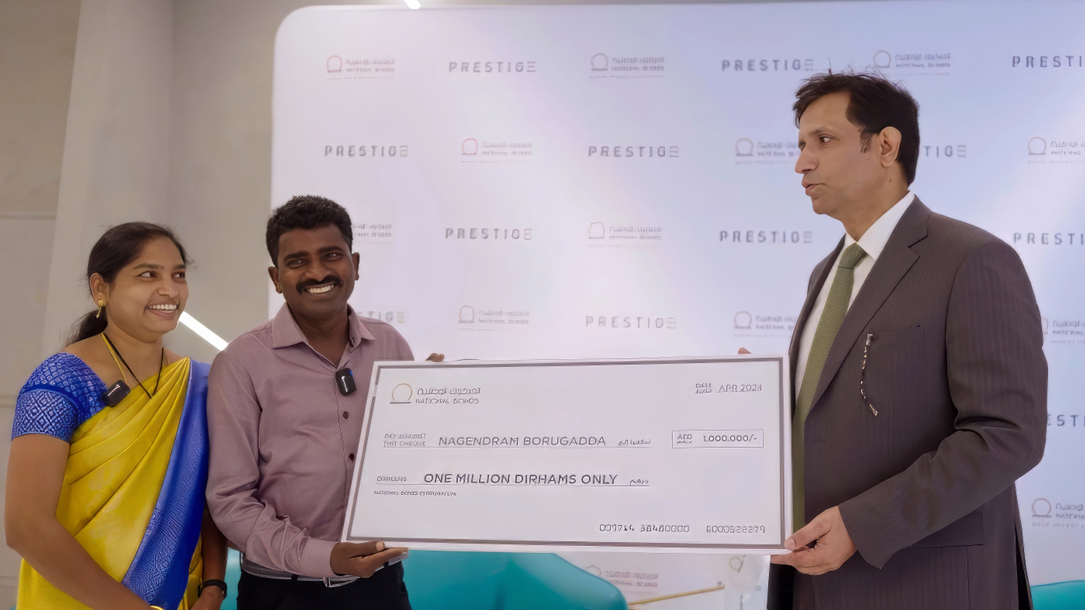 Nagendram Borugadda smiles as he receives his one million dirham prize cheque from a National Bonds representative.